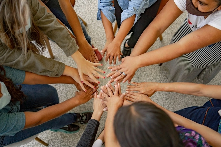 group of people with their hands in the middle of a circle